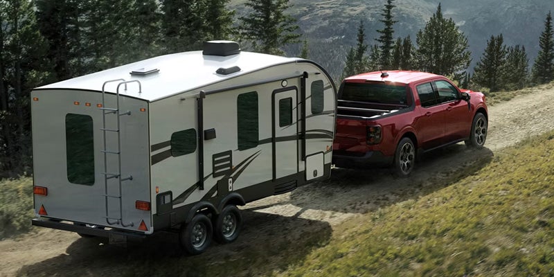 A red 2026 Ford Maverick towing a camper.